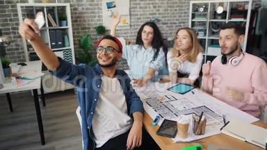 公司员工使用智能手机相机在创意办公室自拍
